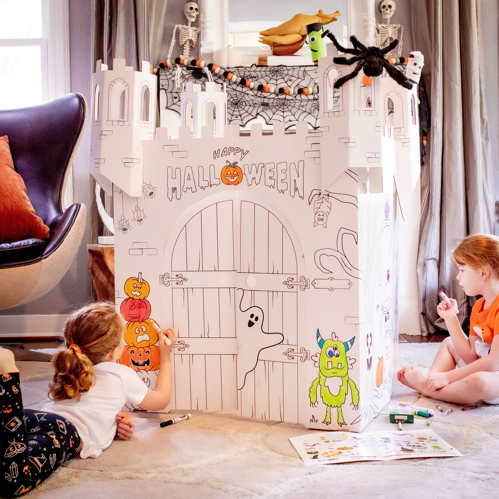 children coloring their cardboard halloween castle playhouse 