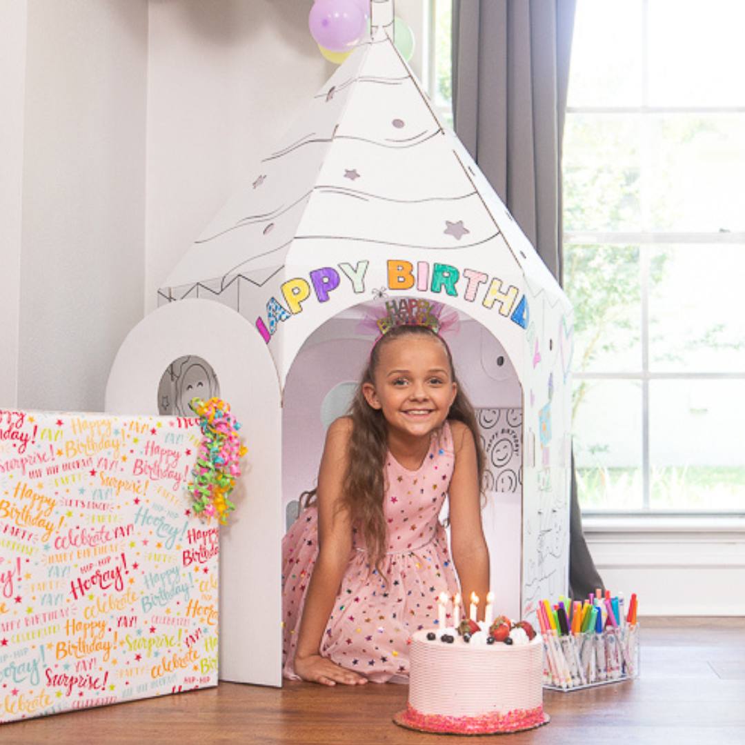 Playboxes birthday cupcake image showing girl sitting in birthday cupcake playhouse with candle on top and a birthday cake in front of her